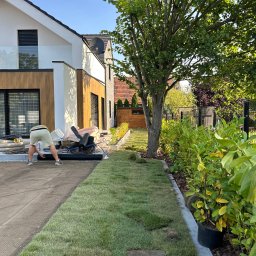 GreenEM Michał Flekiej - Układanie trawy z rolki w Mąkoszycach. Widoczny fragment ułożonego trawnika, przygotowane podłoże i rolki trawy. Prace ogrodnicze przy nowoczesnym domu.