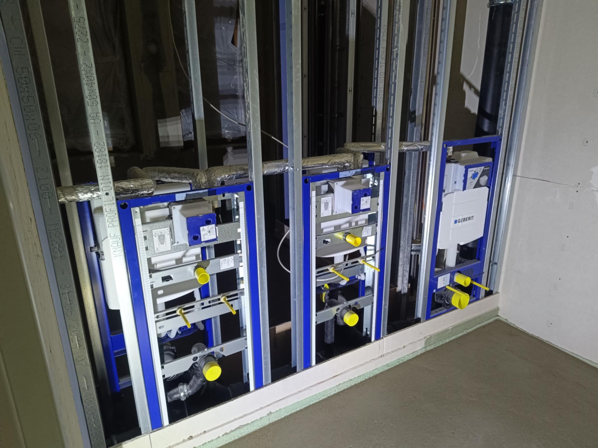 Montaż stelaży podtynkowych Geberit w nowym budownictwie w Wąsoszu, widoczne metalowe profile i rury instalacyjne przed zabudową.