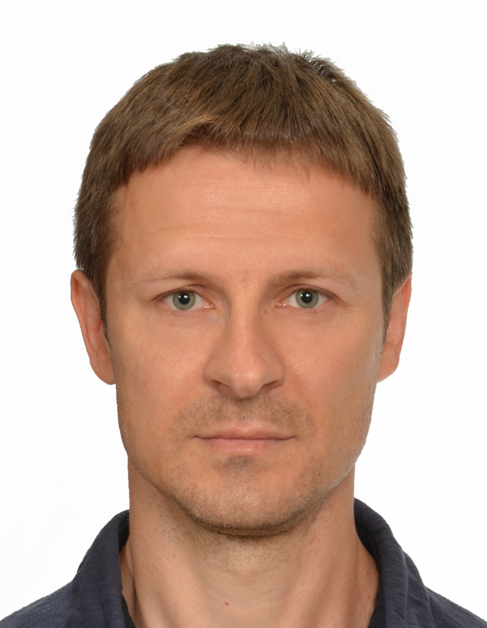 Portret mężczyzny z krótkimi brązowymi włosami i zielonymi oczami na białym tle.