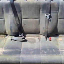 Mateusz Goś - Zabrudzone, tekstylne siedzenie samochodowe z pasami bezpieczeństwa, wymagające czyszczenia. Widoczne plamy, kurz i resztki organiczne na tapicerce.