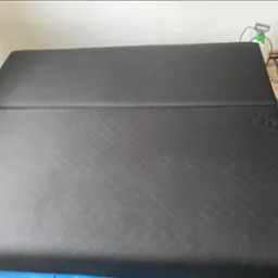 Ciemnoszary, pikowany materac z widocznymi narzędziami do czyszczenia, sugerujący etap po praniu tapicerki. Widok z góry, bez osób.