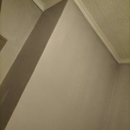 Sabinex - Fragment rogu pokoju z pomalowanymi ścianami w odcieniach beżu, widoczny styk ściany z sufitem i listwa dekoracyjna, sufit z wyraźną fakturą.