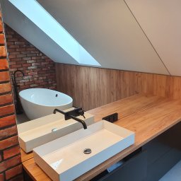 1. MARCUS BUDOWNICTWO I REMONTY WOJCIECH ZWARA - Nowoczesna łazienka na poddaszu: biała wanna wolnostojąca, dwie prostokątne umywalki nablatowe z czarną armaturą, ściana z cegły i drewniane panele ścienne.