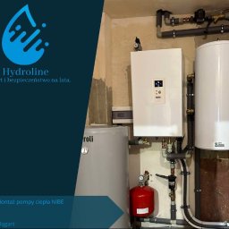 HYDROLINE SPÓŁKA Z OGRANICZONĄ ODPOWIEDZIALNOŚCIĄ - Zestaw urządzeń grzewczych: biała pompa ciepła NIBE wisząca na ścianie, obok biały zasobnik ciepłej wody, szary zbiornik buforowy i czerwone naczynie przeponowe, połączone rurami w kotłowni...