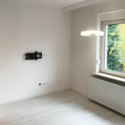 Pomalowany jasny pokój z jasnym laminatem i uchwytem pod telewizor