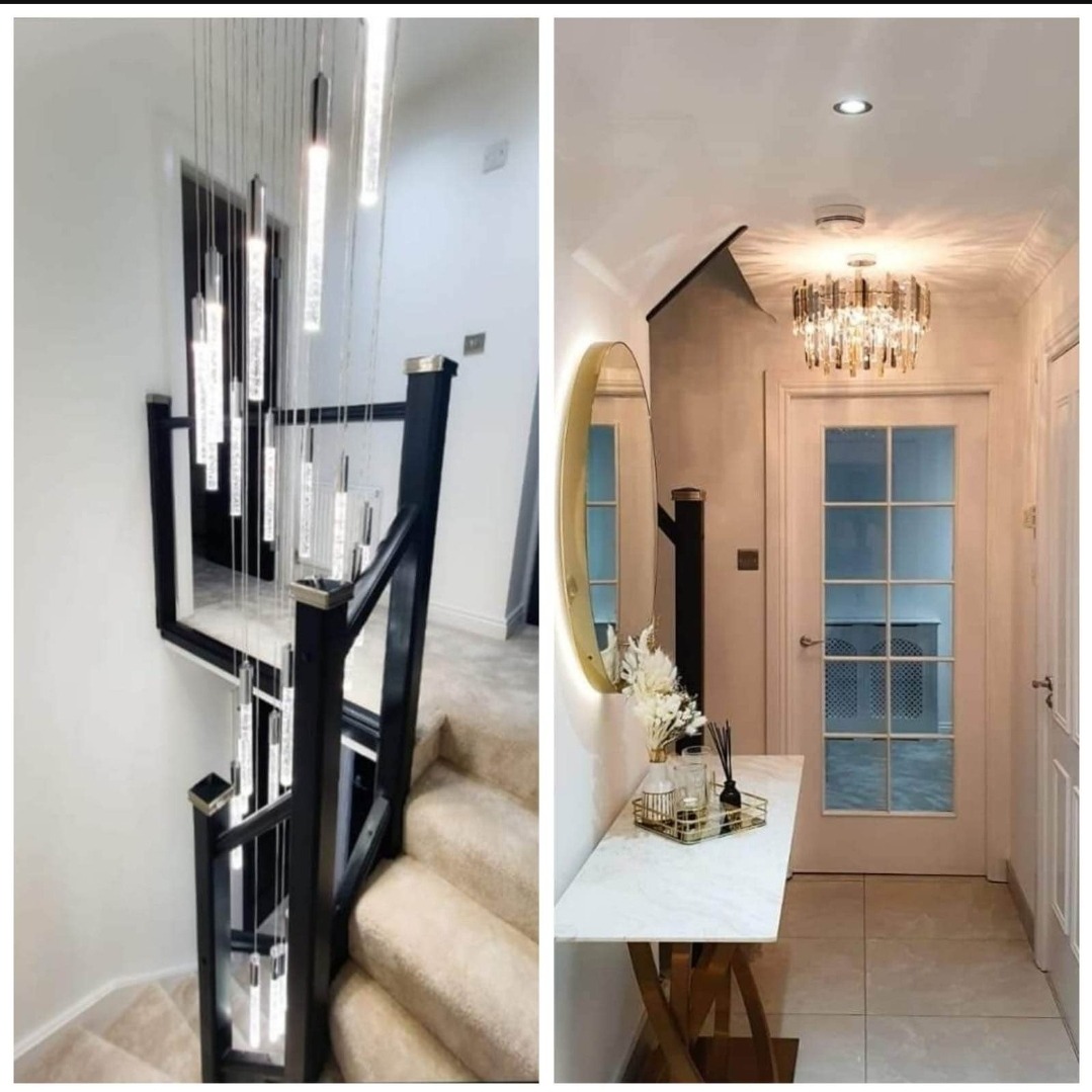 Nowoczesne wnętrze: Schody z czarną balustradą i wiszącą kaskadą kryształowych lamp, obok wejście z okrągłym lustrem podświetlanym LED i konsolą z marmurowym blatem.