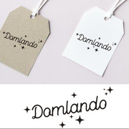 Mangraf Studio - Dwie zawieszki z logo 'Damlando', jedna beżowa, druga biała, leżące na jasnoróżowym tle, poniżej powtórzone logo w czerni.