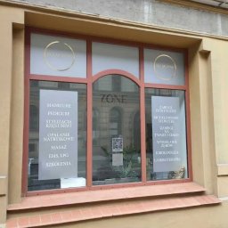 Mangraf Studio - Witryna salonu kosmetycznego z wypisanymi na szybie oferowanymi usługami: manicure, pedicure, stylizacja rzęs i brwi, masaż, zabiegi estetyczne, wybielanie zębów.