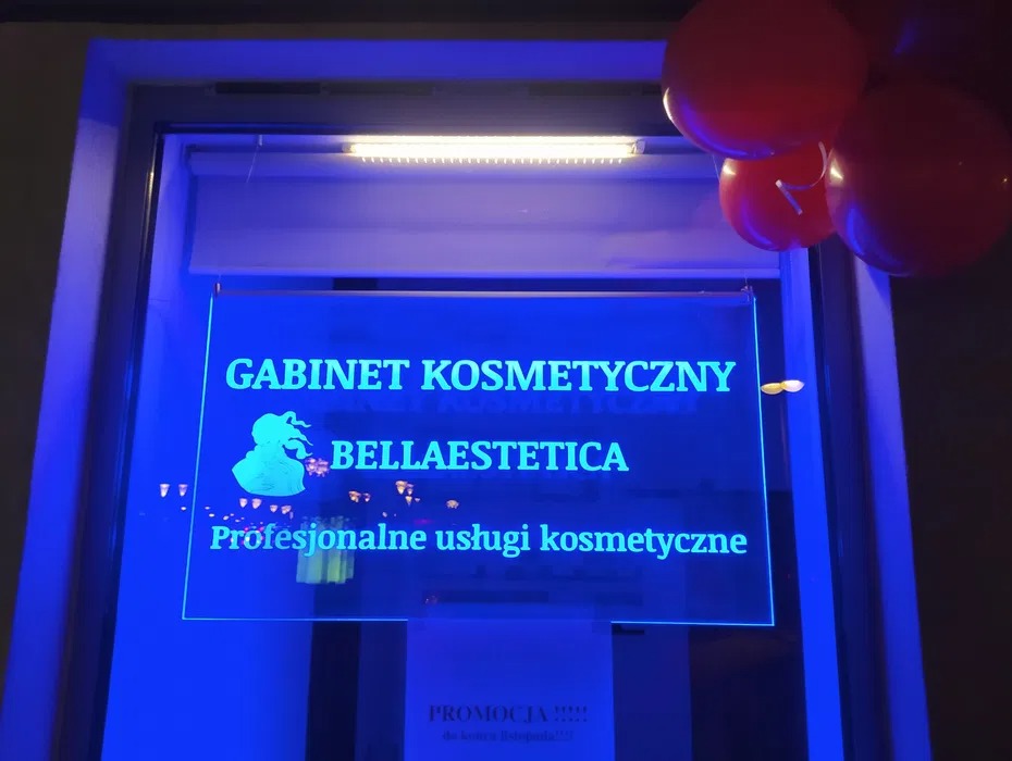 Podświetlany szyld gabinetu kosmetycznego Bellaestetica z logo i napisem Profesjonalne usługi kosmetyczne, udekorowany czerwonymi balonami.
