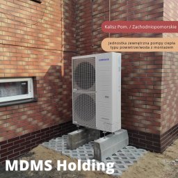 MDMS HOLDING Spółka z o.o. - Zewnętrzna jednostka Samsung typu powietrze/woda, zamontowana na betonowych blokach na tle ceglanej ściany budynku w Kaliszu Pomorskim, województwo Zachodniopomorskie.