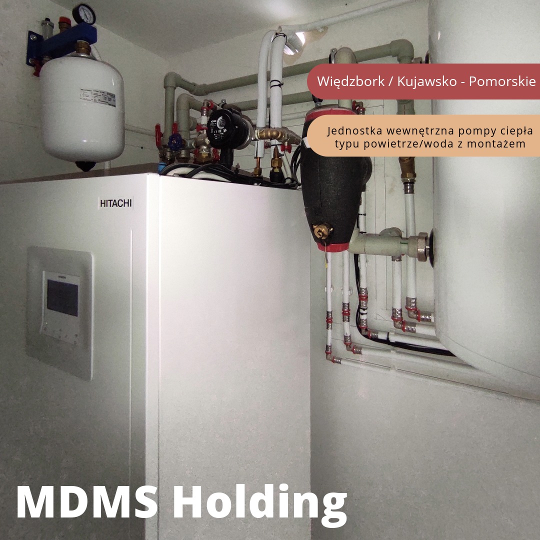 Wewnętrzna jednostka pompy ciepła Hitachi typu powietrze/woda z orurowaniem i zbiornikiem wyrównawczym, zainstalowana w pomieszczeniu technicznym. Widoczne połączenia hydrauliczne i elementy armatury.