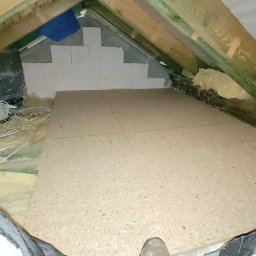 Efneo Fryderyk Migaszewski - Adaptacja strychu: podłoga z płyt OSB ułożona na legarach, widoczne ocieplenie wełną mineralną i częściowo wymurowana ściana szczytowa z bloczków gazobetonowych.