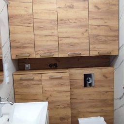 Efneo Fryderyk Migaszewski - Nowoczesna łazienka z zabudową z drewnopodobnej płyty, wisząca toaleta, umywalka nablatowa i marmurowe płytki podłogowe.