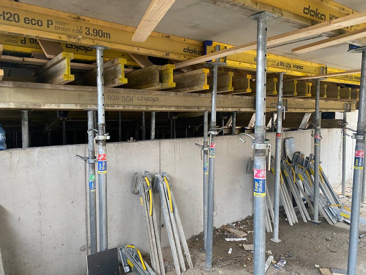 Szare, betonowe ściany z widocznymi szalunkami stropowymi Doka H20 eco podpartymi metalowymi stemplami Eurex 20 eco, przygotowanie do wylewania fundamentów.