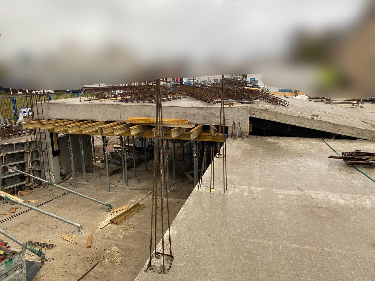 Wylewka betonowa z wystającymi prętami zbrojeniowymi, szalunki drewniane podtrzymujące konstrukcję, widok z góry, plac budowy.