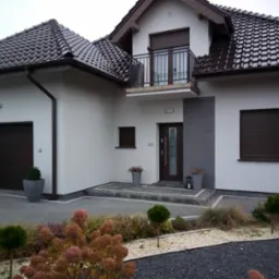 Nowoczesny dom jednorodzinny z brązową stolarką okienną, balkonem i zadbanym ogrodem z kamieniami i roślinami ozdobnymi.