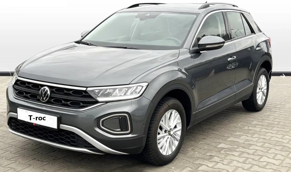Szary Volkswagen T-Roc na tle jasnoszarej kostki brukowej, widok z przodu pod lekkim kątem.
