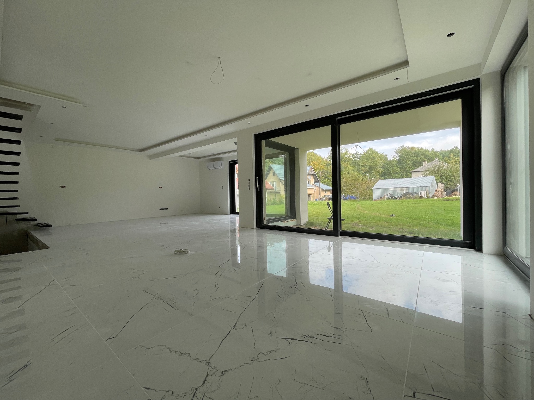 Jasne, przestronne wnętrze z marmurową podłogą i dużymi oknami w Białymstoku. Widok na zewnątrz, minimalistyczny design, nowoczesne wykończenie.