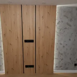 Wykończona ściana z drewnianymi panelami z czarnymi wstawkami i gniazdkami elektrycznymi, obok ściana z dekoracyjnym tynkiem imitującym kamień i białym oknem z widokiem na zewnątrz.