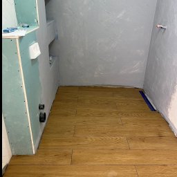 Aleksander Smoleń VentiPRO - Układanie drewnopodobnej glazury w łazience w Myślenicach. Widoczne przygotowane ściany pod wykończenie i odpływ liniowy. Glazurnik Myślenice.