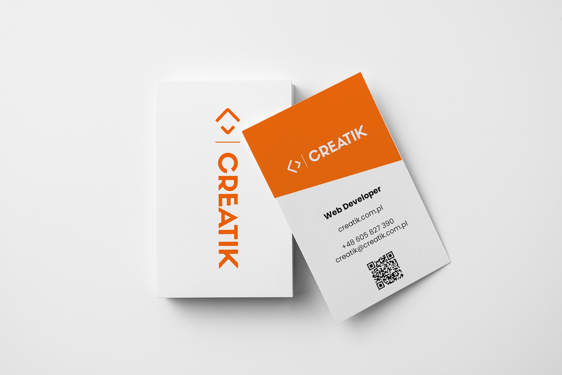 Wizytówki firmy Creatik z pomarańczowym logo i danymi kontaktowymi Web Developera, ułożone na białym tle.