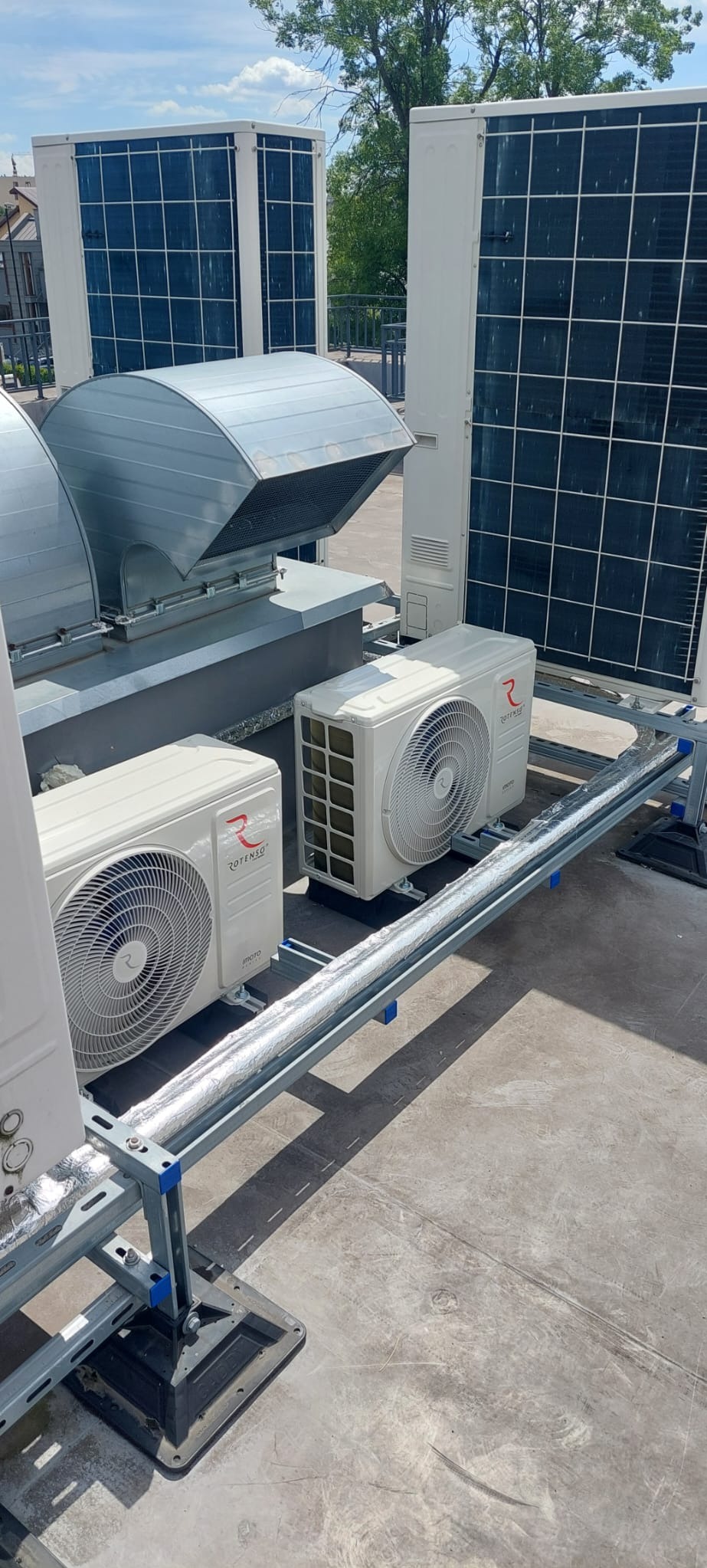 Instalacja klimatyzacji przemysłowej na dachu budynku, widoczne jednostki zewnętrzne Rotenso, kanały wentylacyjne z izolacją termiczną oraz stalowa konstrukcja wsporcza.