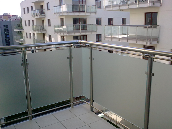 Balkon z balustradą ze stali nierdzewnej i szkła matowego, widok na inne balkony w budynku mieszkalnym.