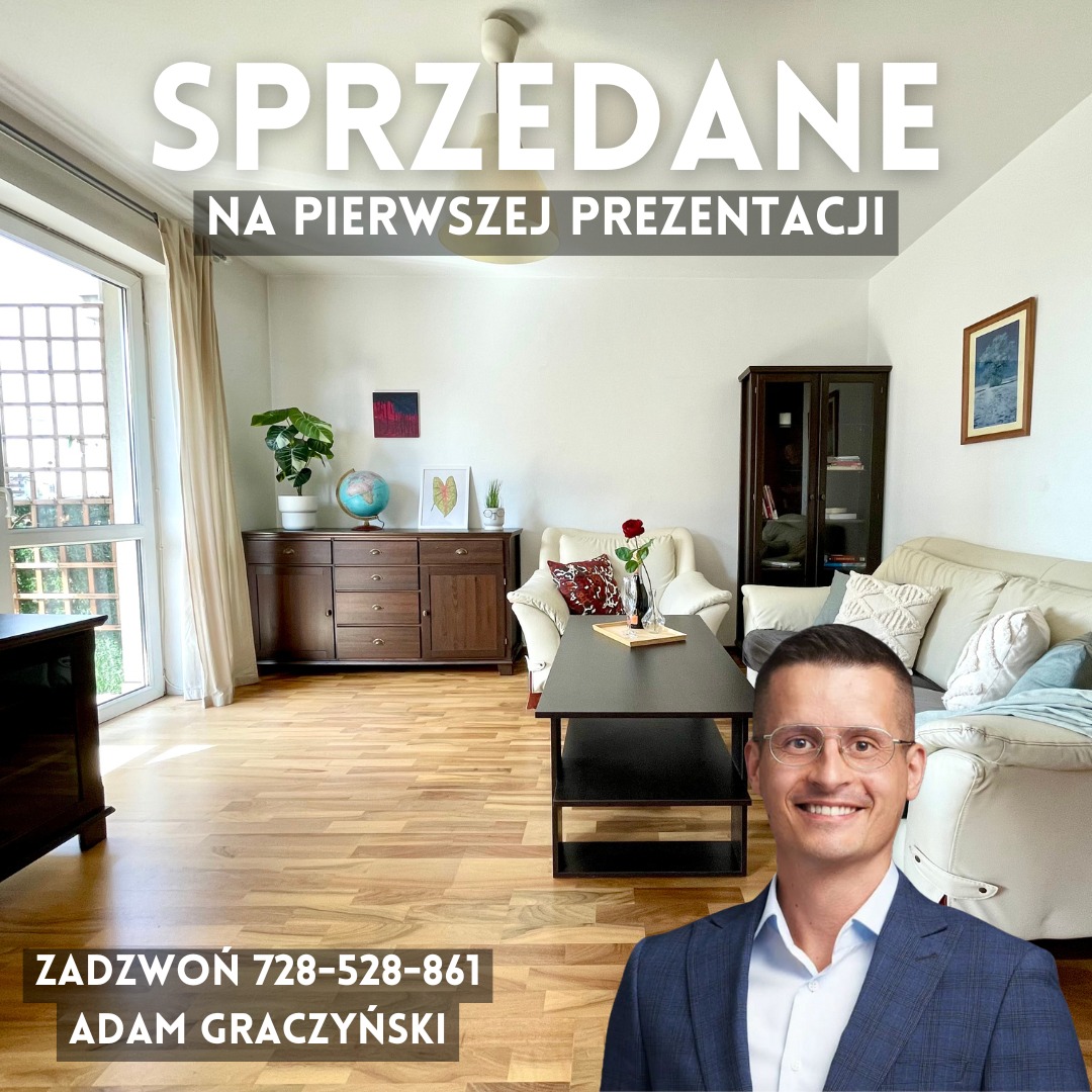 Jasny salon z drewnianą podłogą, kredensem z globusem i rośliną, białym fotelem z czerwoną poduszką, beżową sofą oraz uśmiechniętym agentem nieruchomości w prawym dolnym rogu. Na zdjęciu widnieje...