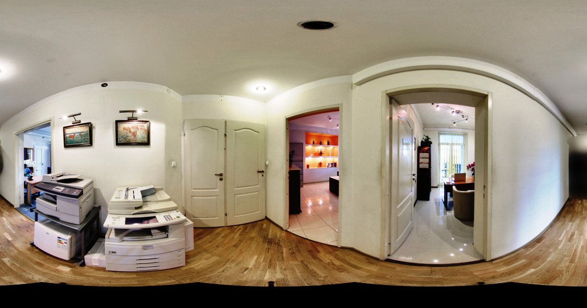 Wnętrze biura rachunkowego z dwoma kserokopiarkami, drewnianą podłogą i widokiem na inne pomieszczenia, prezentowane w formacie panoramicznym.