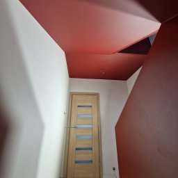 AS-BUD DAMIAN KANIA - Korytarz po remoncie z pomalowanym na czerwono sufitem o nietypowym kształcie i zamontowanymi drewnianymi drzwiami z przeszkleniami.