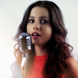 GREGOR HOME STUDIO - Młoda kobieta z brązowymi, falowanymi włosami śpiewa do srebrnego mikrofonu w stylu retro, z delikatnym rozświetleniem na twarzy.