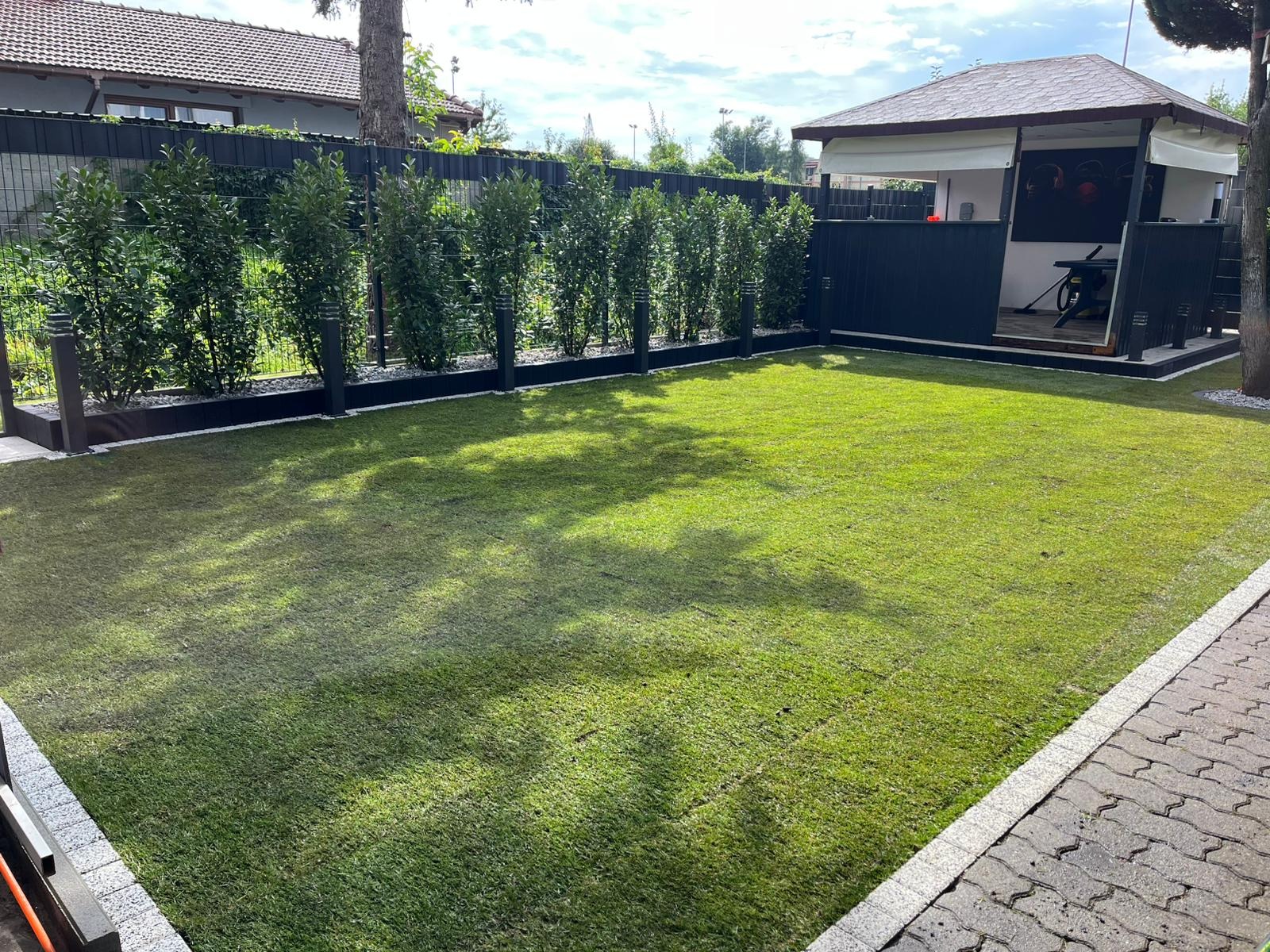 Starannie założony trawnik z rolki w Cybince, z równo przyciętą trawą i estetycznie wykończonymi rabatami wzdłuż ogrodzenia. Widoczna altana w tle.