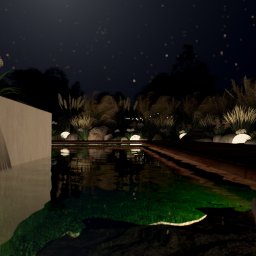 Monika Lewandowska - Ogrody i wnętrza - Nastrojowy ogród nocą w Orłach: oświetlony zbiornik wodny otoczony roślinnością i kamieniami, tworzący relaksującą atmosferę.