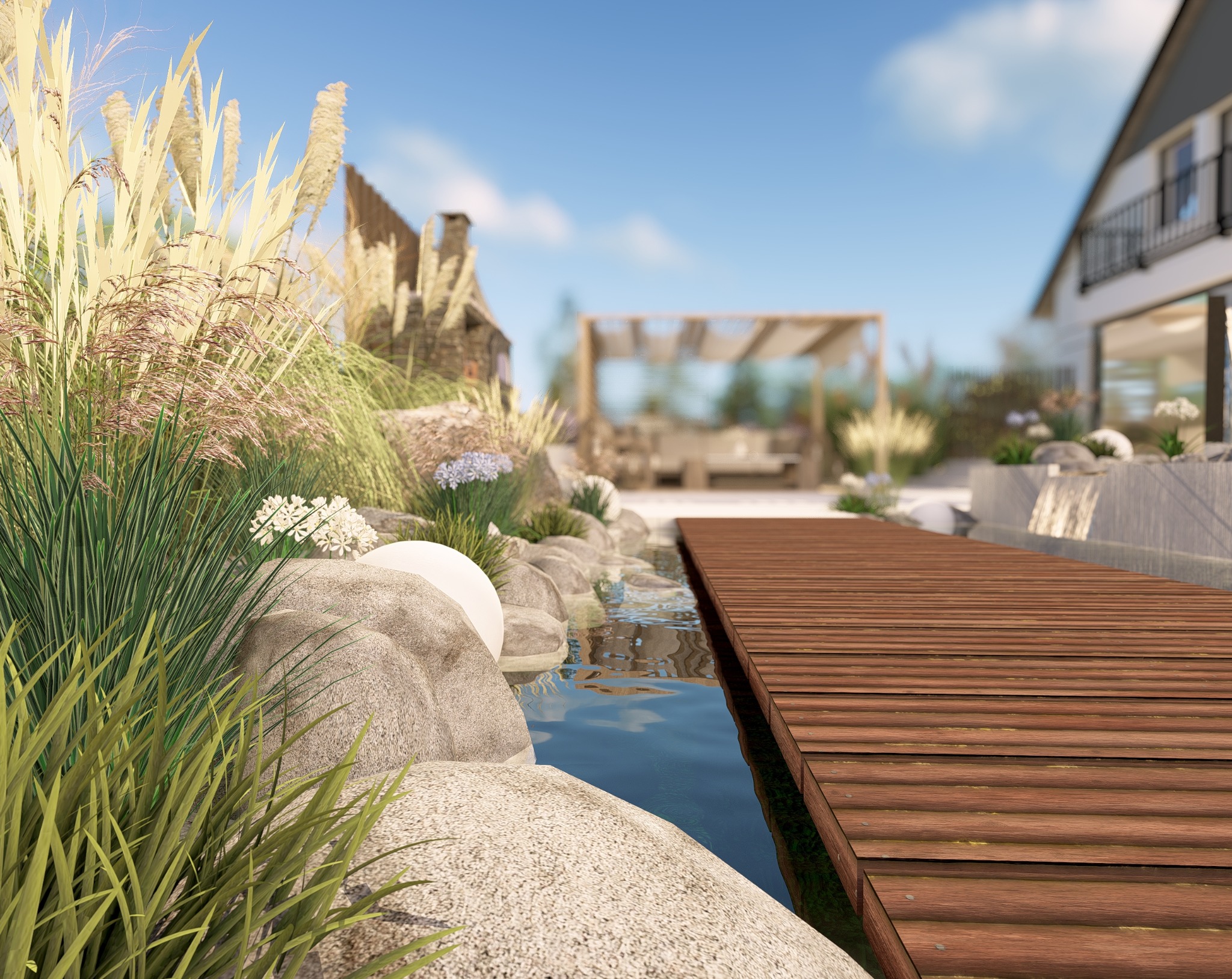 Oczko wodne z drewnianym mostkiem i roślinnością ozdobną na pierwszym planie, w tle dom z tarasem i pergola. Elementy małej architektury ogrodowej.