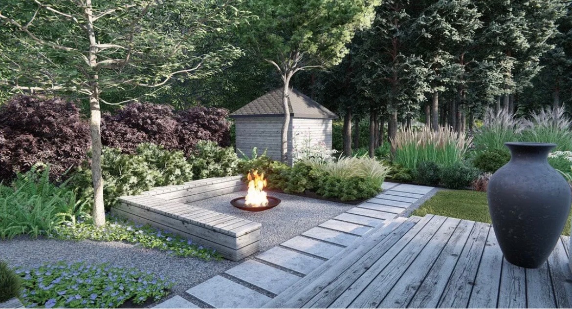 Ogród z miejscem na ognisko otoczonym drewnianą ławką, widoczne ozdobne trawy, ścieżka z płyt betonowych i duży wazon ceramiczny na drewnianym tarasie.