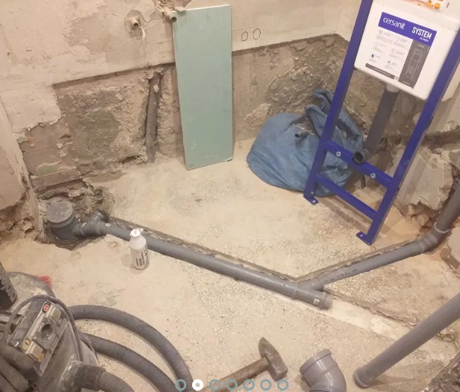 Przygotowanie do montażu podwieszanej toalety: widoczne rury kanalizacyjne, stelaż z marką Cersanit, fragment płyty karton-gips i surowe ściany w trakcie prac instalacyjnych.