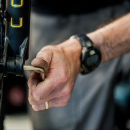 Magdalena Ramach-Nowak - Mężczyzna w zegarku dokręca śrubę w przednim kole roweru za pomocą klucza imbusowego; widoczne detale opony Sunringle.