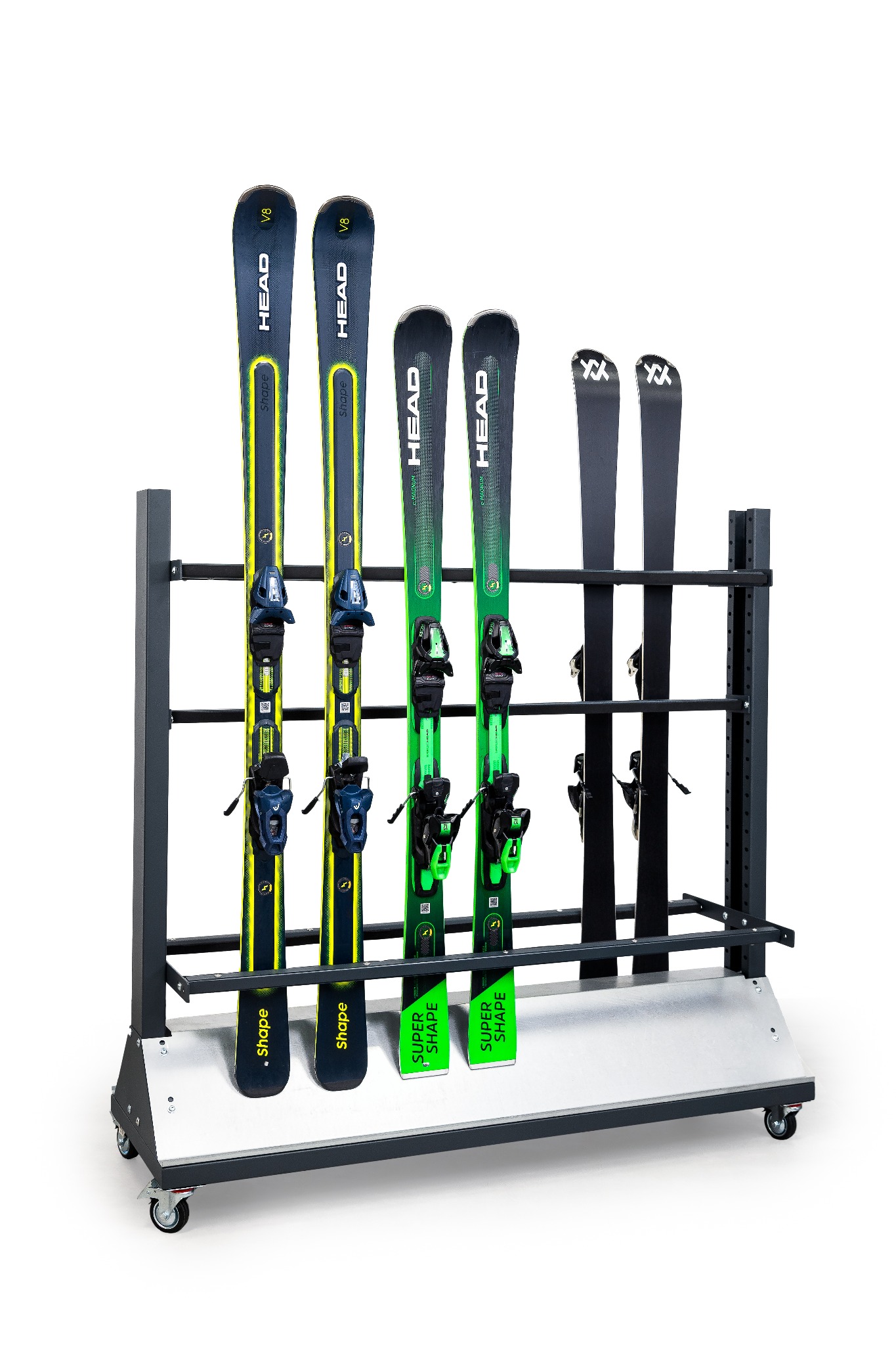 Regał na kółkach z trzema parami nart różnych modeli: Head V8 w kolorze granatowo-żółtym, Head Super Shape w kolorze zielonym oraz Volkl w kolorze czarnym.