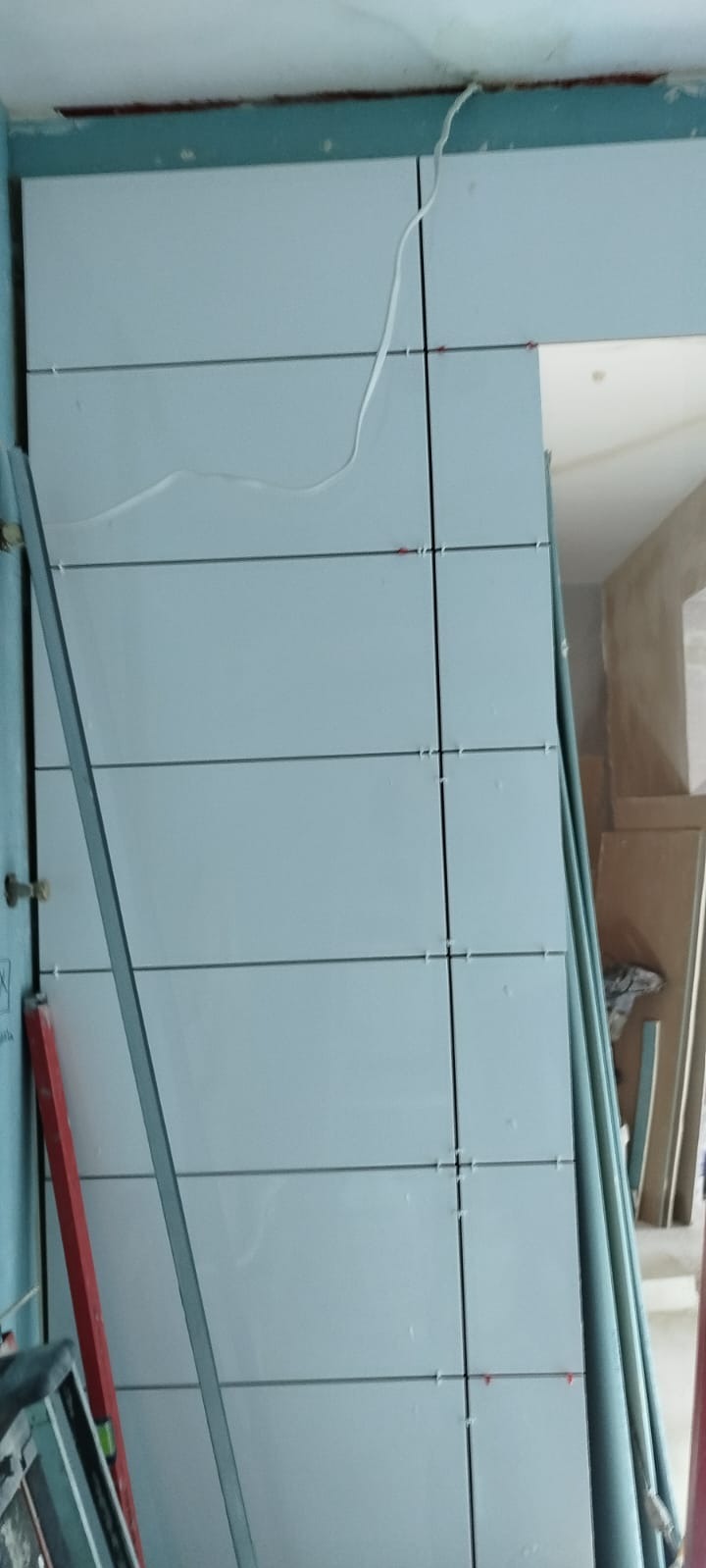 Montaż płyt kartonowo-gipsowych na ścianie, widoczne profile i krzyżyki dystansowe, surowy stan wykończenia.