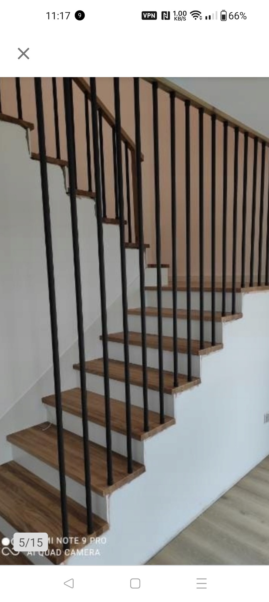 Klatka schodowa z drewnianymi stopniami i czarnymi metalowymi balustradami pionowymi, widok z dołu, minimalistyczny design.