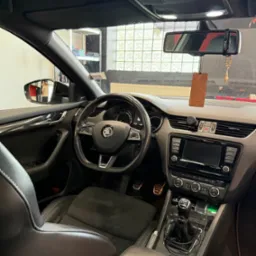 Wnętrze samochodu Skoda Octavia RS z czarną skórzaną tapicerką i elementami karbonowymi. Widoczna deska rozdzielcza, kierownica, fotele i dźwignia zmiany biegów.