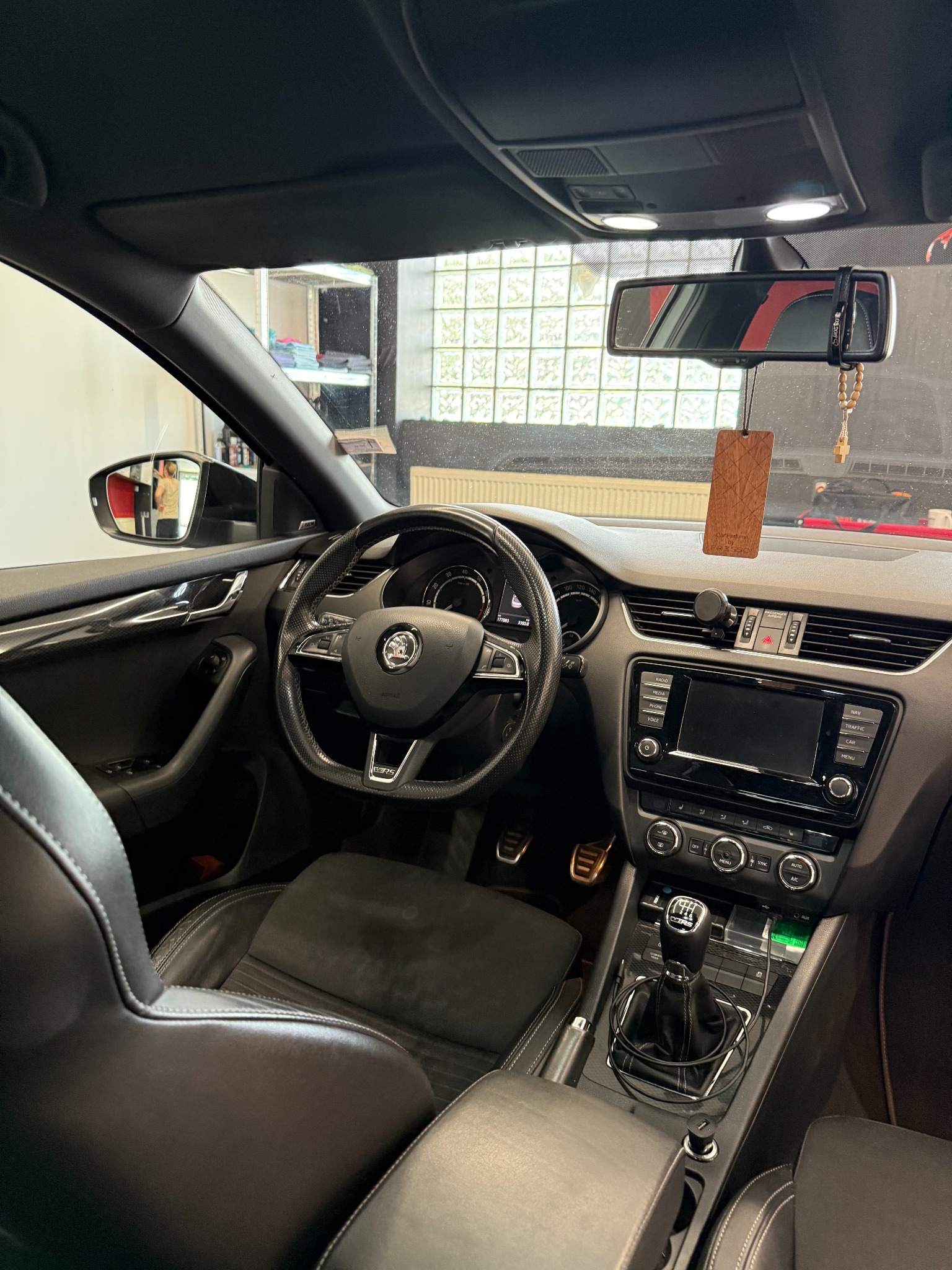 Wnętrze samochodu Skoda Octavia RS z czarną skórzaną tapicerką i elementami karbonowymi. Widoczna deska rozdzielcza, kierownica, fotele i dźwignia zmiany biegów.