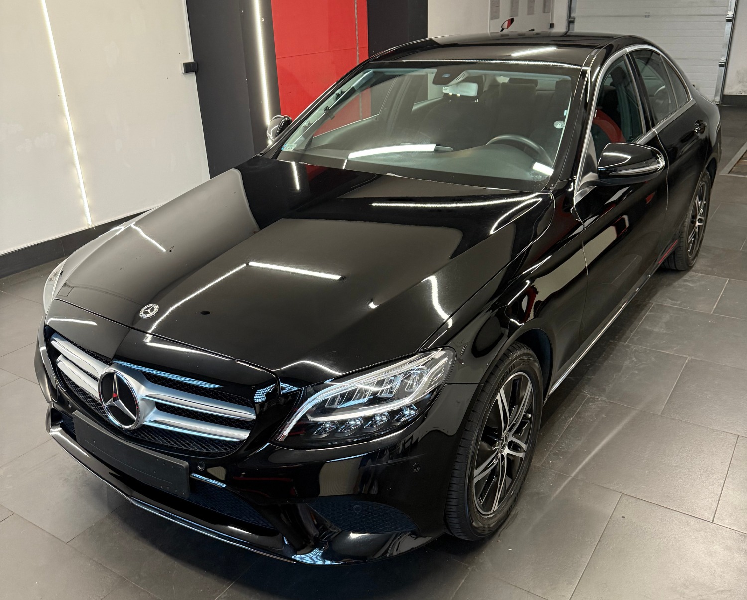 Błyszczący, czarny Mercedes klasy C po myciu, widok z przodu. Reflektory i grill wyraźnie odbijają światło, podkreślając czystość lakieru.