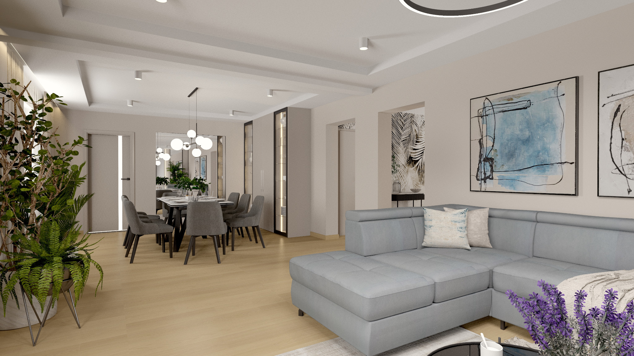 Jasne wnętrze mieszkania z szarym narożnikiem, stołem jadalnym z szarymi krzesłami i dużymi roślinami doniczkowymi po bokach.