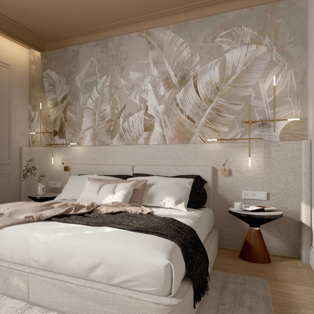Jasna sypialnia z łóżkiem kontynentalnym, beżowym zagłówkiem i tapetą w liście bananowca. Po bokach łóżka stoliki nocne z lampkami i kontaktami.