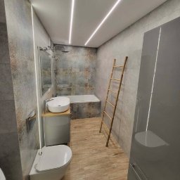 Emil Czesak - Nowoczesna łazienka z szarą mozaiką, podwieszaną toaletą, umywalką nablatową na szafce z drewnianym blatem, bambusową drabinką i podświetleniem LED na suficie i ścianie.