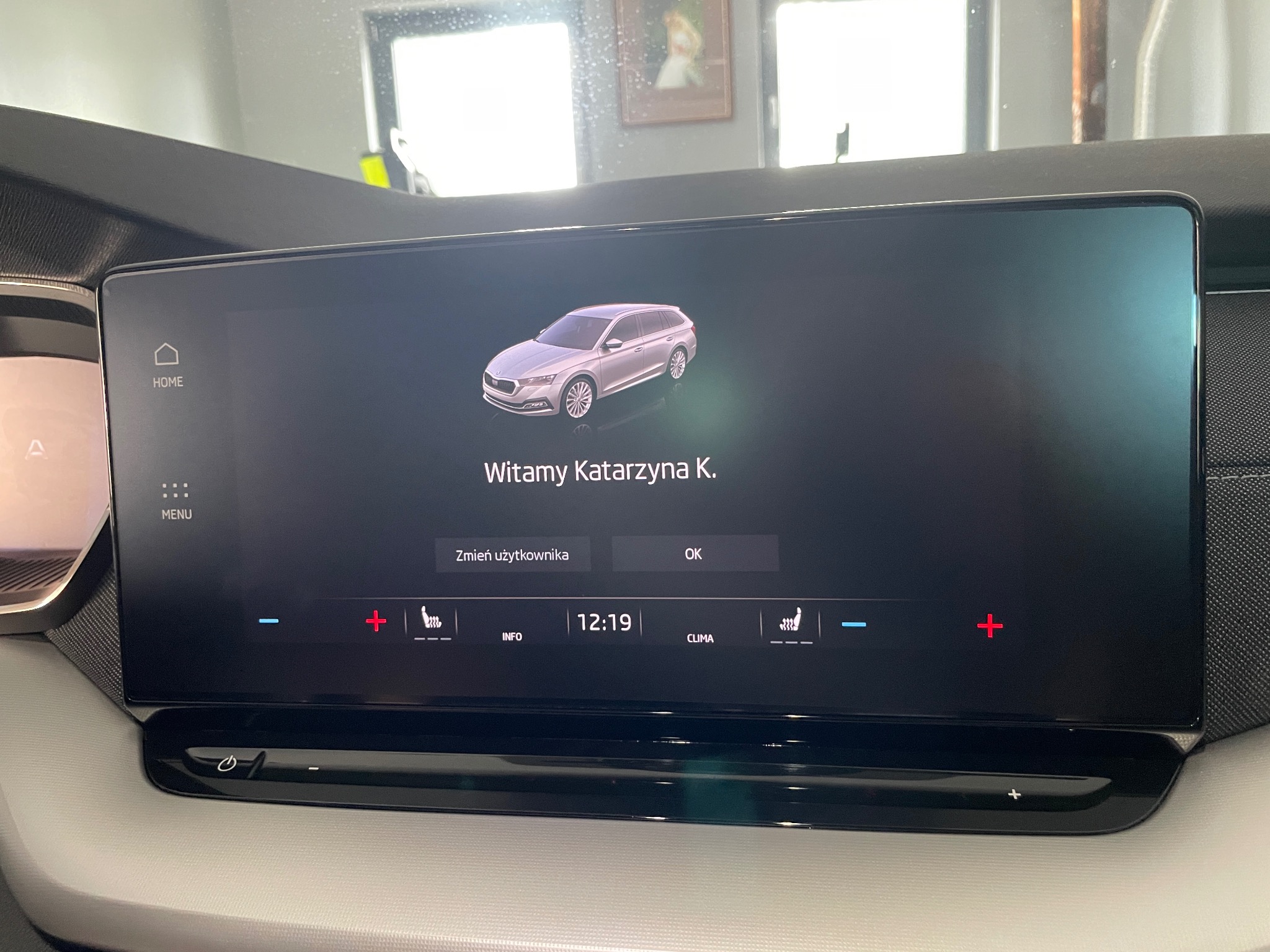 Centralny ekran dotykowy samochodu Skoda wyświetlający powitanie użytkownika Katarzyna K. z ustawieniami klimatyzacji i regulacją foteli.