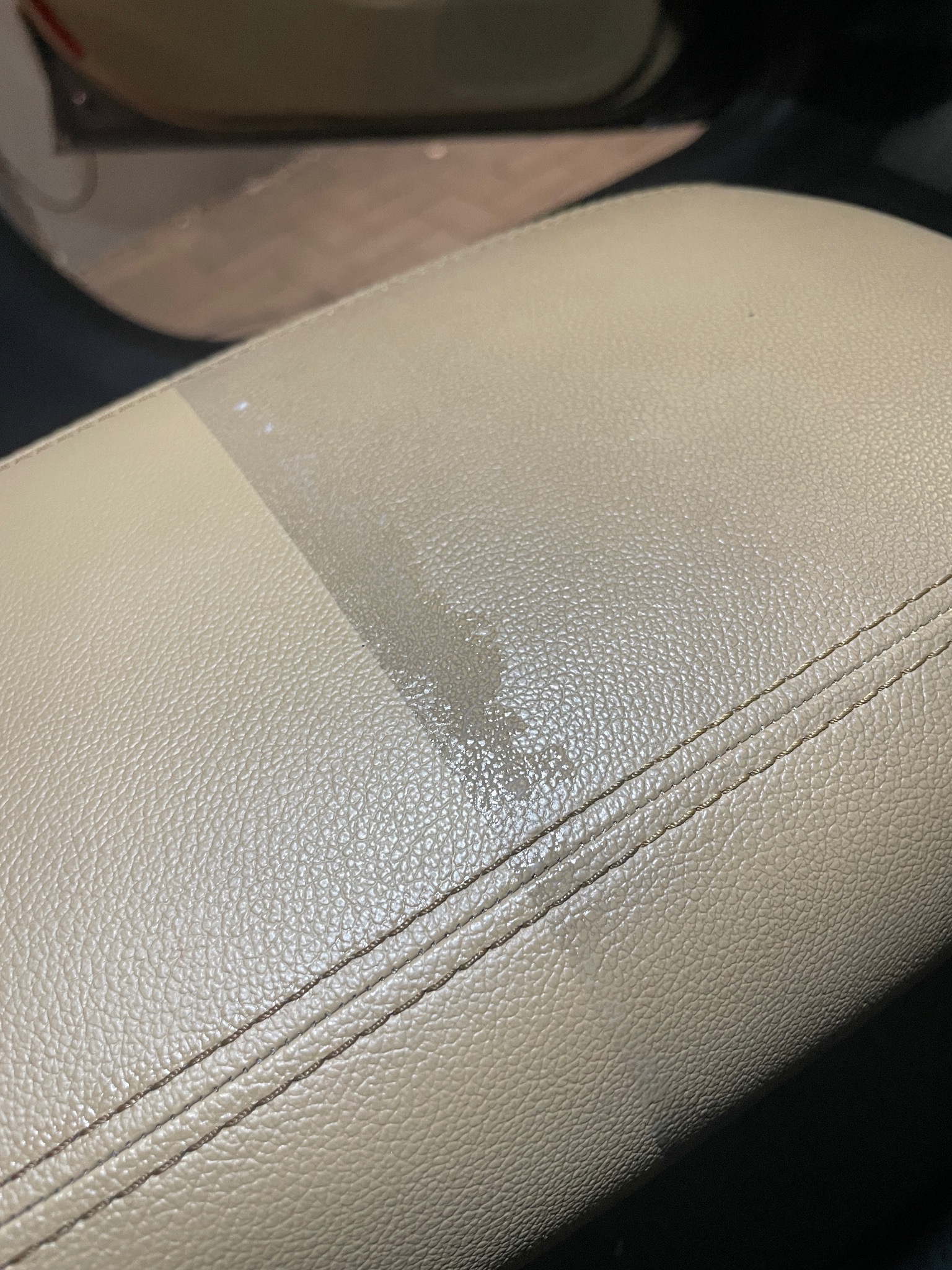 Fragment jasnej, skórzanej tapicerki samochodowej, widoczna różnica w czystości po praniu na fragmencie powierzchni.