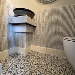 Łazienka i Dom Melchior Nowociński - Nowoczesna łazienka z marmurowymi płytkami ściennymi, wzorzystą posadzką i oryginalną umywalką w kształcie misy na marmurowym blacie.