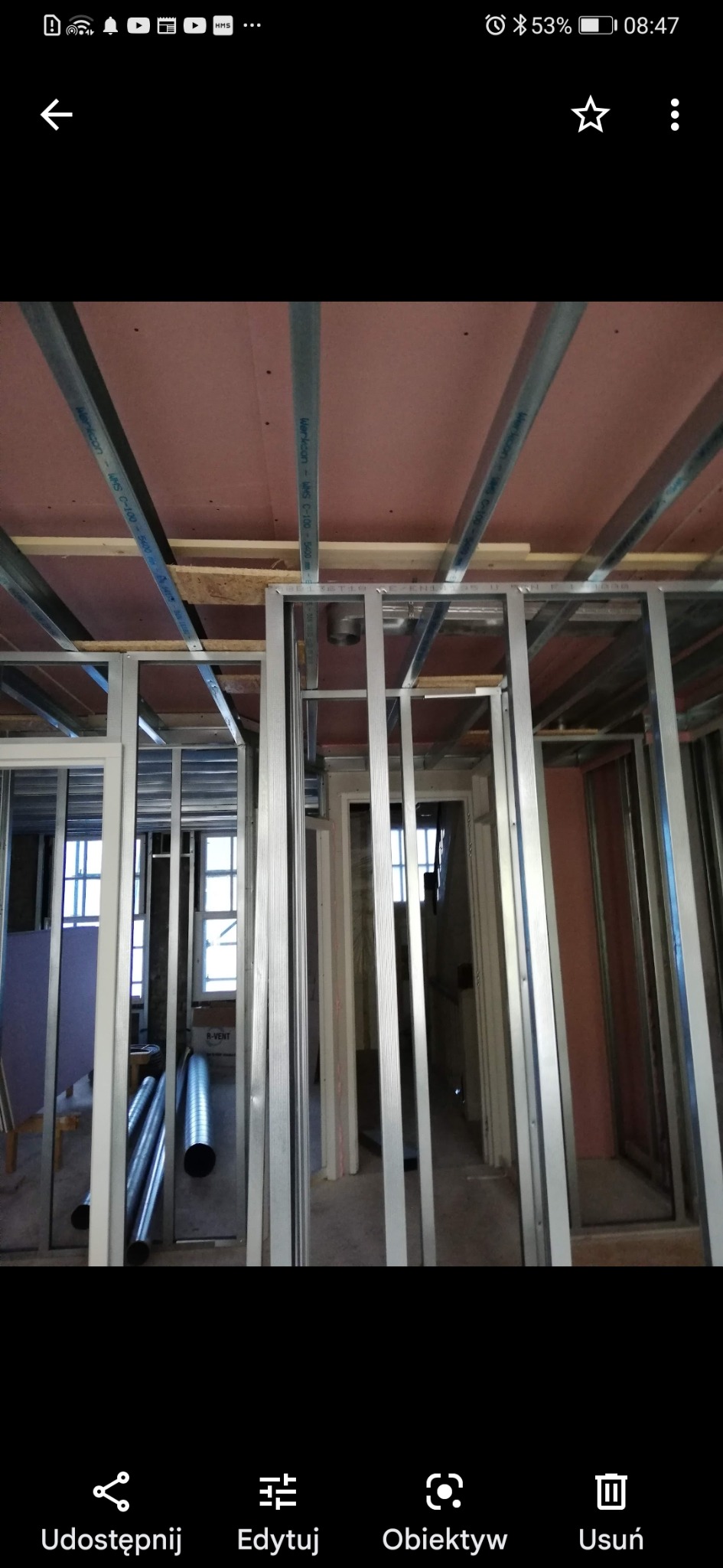 Konstrukcja szkieletowa ścian działowych z profili stalowych w trakcie montażu, widoczne profile sufitowe, instalacja wentylacyjna, płyty kartonowo-gipsowe w tle.